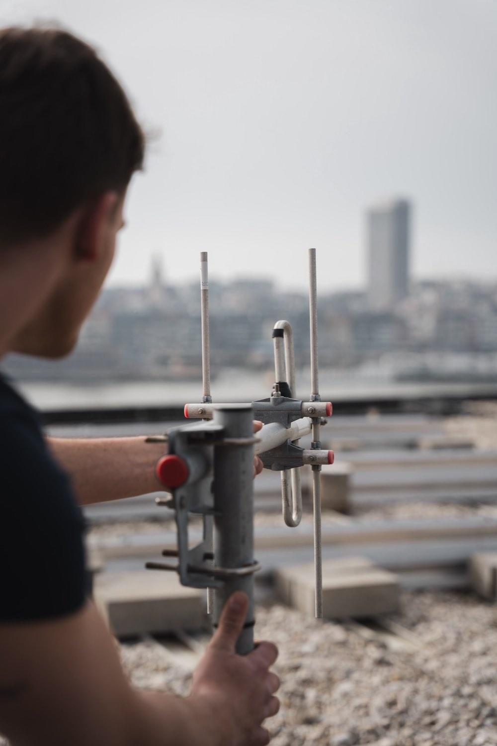 Yunite-technicus monteert een buitenantenne op het dak voor gsm-versterking in een bedrijfsgebouw.