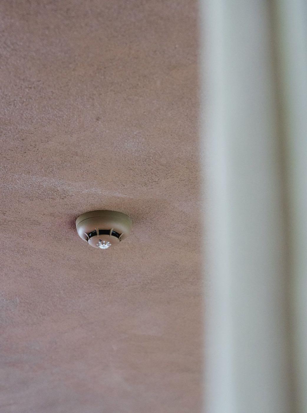 Rookdetector aan het plafond van een afgewerkte bedrijfsruimte.